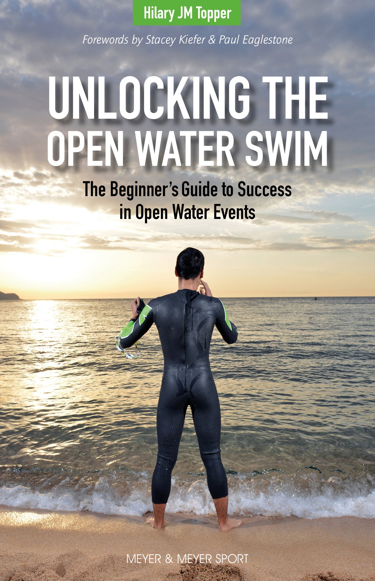 Book cover for 'Unlocking the Open Water Swim' by Hilary JM Topper, showing a swimmer in a black and green wetsuit standing on a sandy beach at sunset facing the water.